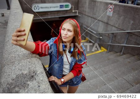 Woman takes selfie near metro station. 69469422