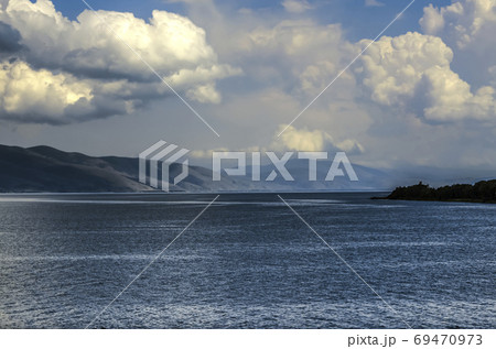 Darkened sky with huge cumulus clouds hanging over the mountain lake Sevan, located in the mountains of Armenia 69470973