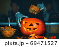 man cutting a jack-o-lantern pumpkin to halloween celebration. 69471527