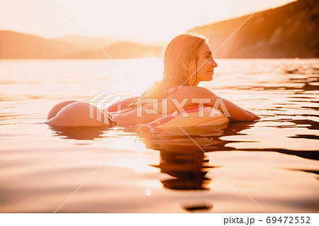 Young attractive girl with sexy body relax in the sea at warm sunset 69472552