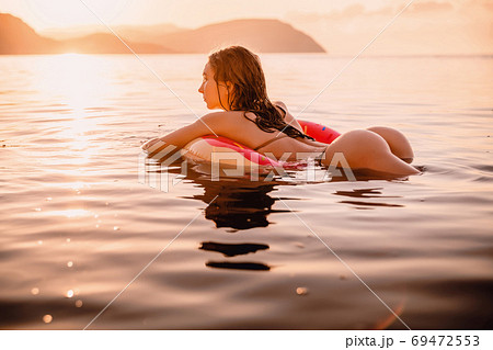 Young attractive girl with sexy body relax in the sea at warm sunset Young attractive girl with sexy body relax in the sea at warm sunset 69472553