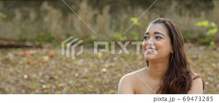 Portrait of happy young beautiful Indian woman thinking at the park 69473285