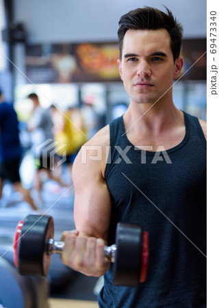 Young handsome man exercising with dumbbells at the gym 69473340