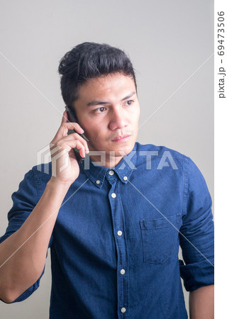 Young handsome Asian businessman thinking while talking on the phone 69473506