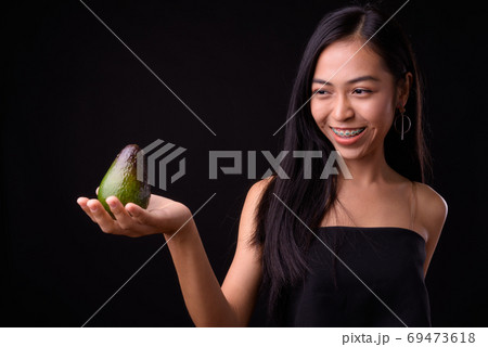 Portrait of happy young beautiful Asian woman holding avocado 69473618