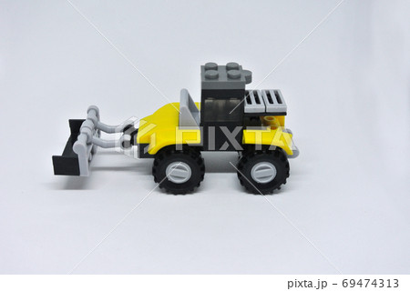 Toy Bulldozer made from yellow and black plastic bricks and with wheels isolated on a white background. Toy Bulldozer made from yellow and black plastic bricks and with wheels isolated on a white background. 69474313