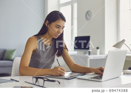 Young woman working on graphic design project using modern tablet and laptop computer 69474388