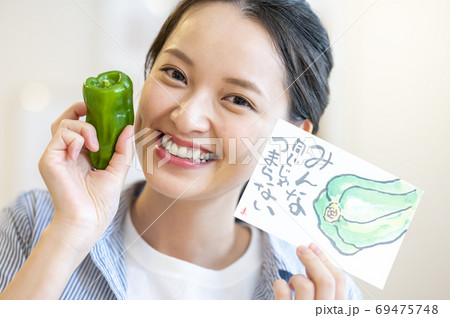 野菜のピーマンとそのイラストをもつ 若い女性の写真素材