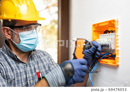 Electrician at work with face protected by surgical mask to prev 69476053