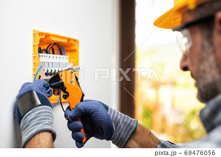 Electrician at work with safety equipment on a residential elect Electrician at work with safety equipment on a residential elect 69476056