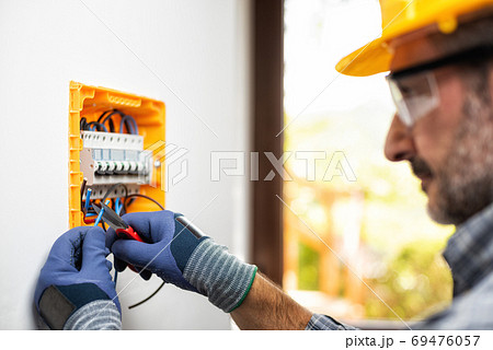 Electrician at work with safety equipment on a residential elect Electrician at work with safety equipment on a residential elect 69476057