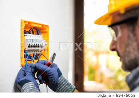 Electrician at work with safety equipment on a residential elect Electrician at work with safety equipment on a residential elect 69476058