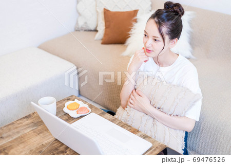 パソコンを見ながらおやつを食べる若い女性 69476526
