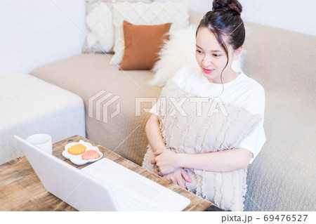 パソコンを見ながらおやつを食べる若い女性 パソコンを見ながらおやつを食べる若い女性 69476527