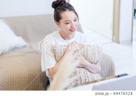 パソコンを見ながらおやつを食べる若い女性 69476528