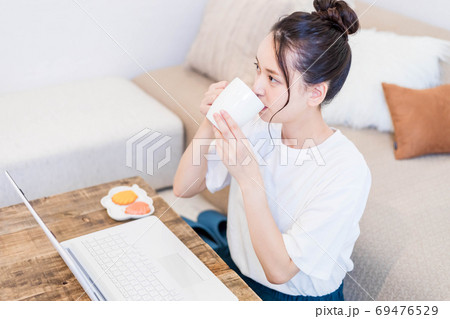 パソコンを見ながらおやつを食べる若い女性 パソコンを見ながらおやつを食べる若い女性 69476529