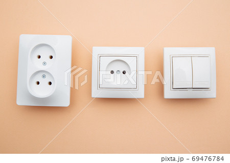Power sockets and switch on pink table, minimalism concept Power sockets and switch on pink table, minimalism concept 69476784