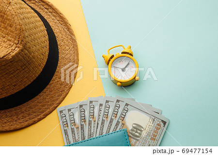 Time for summer vacation. Hat and passport with money banknotes on yellow blue background Time for summer vacation. Hat and passport with money banknotes on yellow blue background 69477154