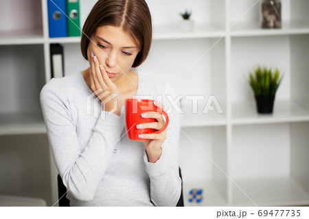 Beautiful young woman suffering from terrible severe toothache, touching cheek with hand. 69477735