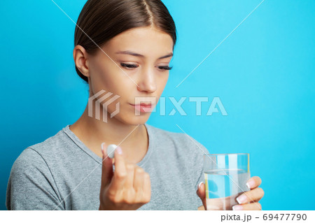 Close up of a woman taking pills holding glass of water 69477790