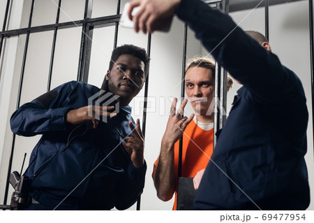 Theme party on the theme of prison. The guys take a fun selfie with each other on their smartphone. Theme party on the theme of prison. The guys take a fun selfie with each other on their smartphone. 69477954