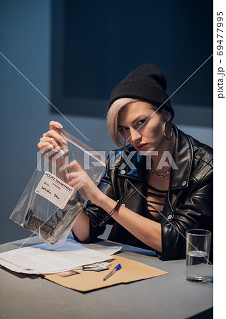 A young girl criminal from a gang was caught with a gun and is photographed with it at a police station A young girl criminal from a gang was caught with a gun and is photographed with it at a police station 69477995