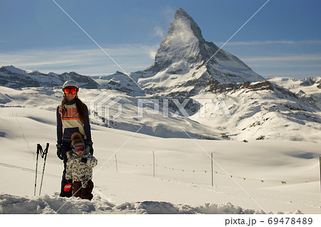 Young smiling woman and little child standing in deep snow on backgroung of Matterhorn Switzerland. Happy family Young smiling woman and little child standing in deep snow on backgroung of Matterhorn Switzerland. Happy family 69478489