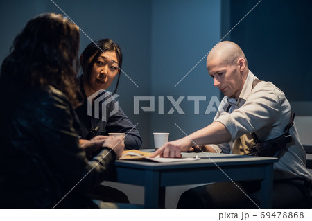 An experienced investigator and a female police officer interrogate the suspect An experienced investigator and a female police officer interrogate the suspect 69478868