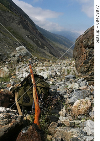 Backpack and rifle hunter on the rocks at the entrance to the rise in the valley 69478977