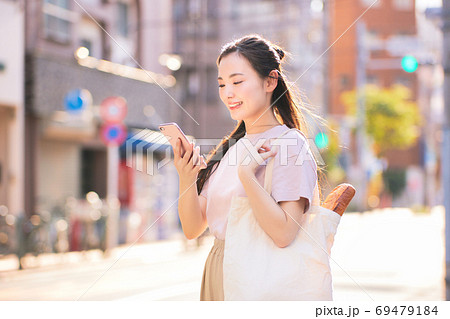 街中でスマホを持つ買い物帰りの若い女性 街中でスマホを持つ買い物帰りの若い女性 69479184