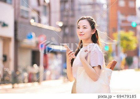 街中でスマホを持つ買い物帰りの若い女性 街中でスマホを持つ買い物帰りの若い女性 69479185