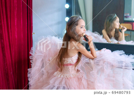 Ballerina little cute girl wear pink dress sitting on a chair in 69480793