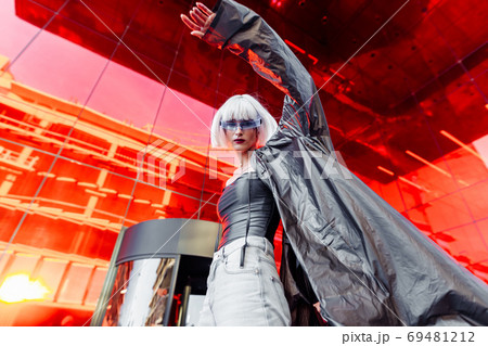 Stylish futuristic blonde in cyberpunk style on a red mirror background. Stylish futuristic blonde in cyberpunk style on a red mirror background. 69481212