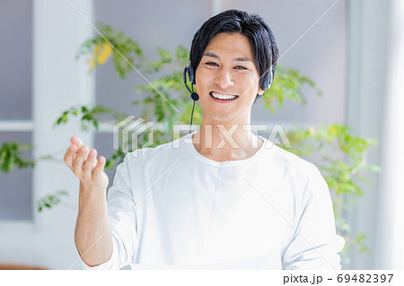 ヘッドセットをつけて画面の外に向かって話をする若い男性 ヘッドセットをつけて画面の外に向かって話をする若い男性 69482397