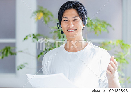 ヘッドセットをつけて画面の外に向かって話をする若い男性 ヘッドセットをつけて画面の外に向かって話をする若い男性 69482398