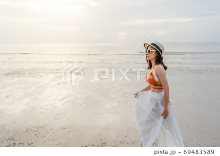 cheerful woman in bikini walking on sea beach 69483589