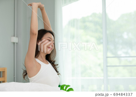 Woman stretching her arm after wake up on bed and looking outside windows in bedroom feeling so fresh and relax in the morning,Healthcare Concept Woman stretching her arm after wake up on bed and looking outside windows in bedroom feeling so fresh and relax in the morning,Healthcare Concept 69484337