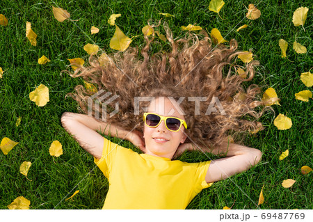 Beautiful girl lying on lawn with yellow leaves in 69487769