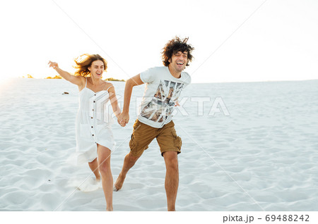 Cheerful couple in love running on the beach and enjoying their vacation 69488242
