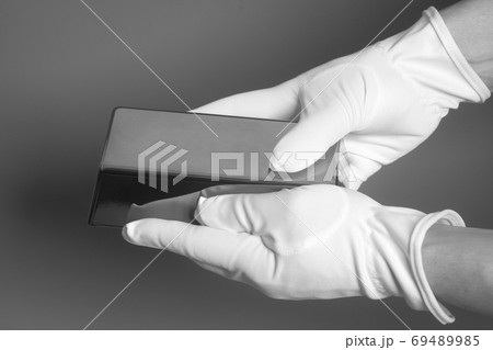 Men's hand in white gloves holding a silver bullion 69489985