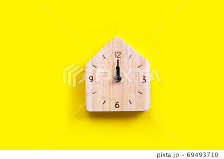 Miniature house wooden clock on yellow background. Miniature house wooden clock on yellow background. 69493710
