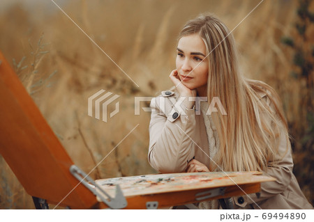 Woman in a brown coat painting in a field Woman in a brown coat painting in a field 69494890