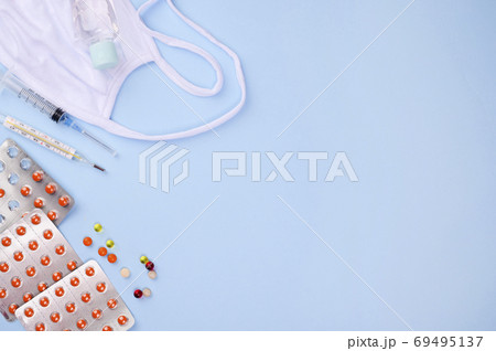 Orange tablets in the package, an injection syringe, a thermometer, a medical face shield and a Orange tablets in the package, an injection syringe, a thermometer, a medical face shield and a 69495137
