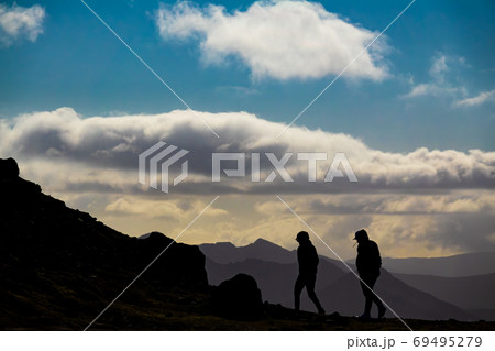 Two persons silhouette walking on top of the mountain Two persons silhouette walking on top of the mountain 69495279