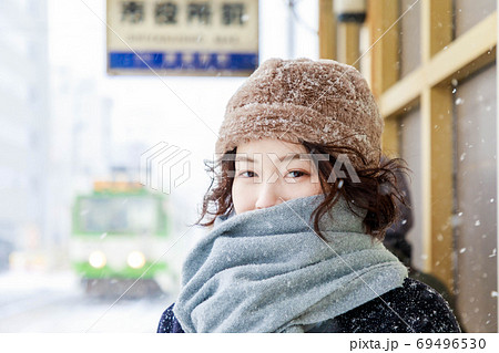 雪の降る駅で市電を待つ旅行者の女性 69496530