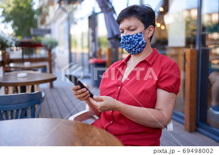 Beautiful mature woman with with dark hair in a handmade protective mask Beautiful mature woman with with dark hair in a handmade protective mask 69498002