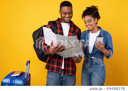 Couple Choosing Travel Destination With Smartphone And Map In Studio Couple Choosing Travel Destination With Smartphone And Map In Studio 69498278