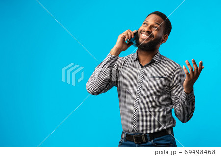 Smiling black guy talking on cell phone, blue background Smiling black guy talking on cell phone, blue background 69498468