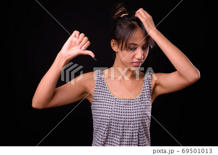 Young beautiful Asian woman against black background Young beautiful Asian woman against black background 69501013