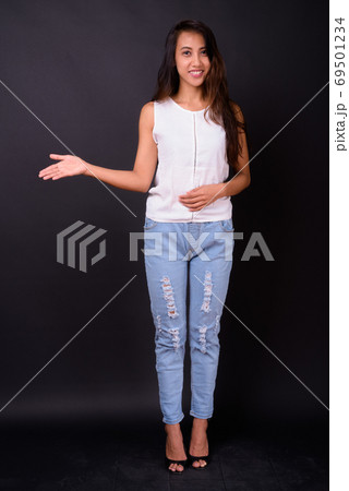 Young beautiful Asian woman against black background Young beautiful Asian woman against black background 69501234